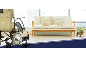 A wheelchair and a couch in a common area at a long-term care home.