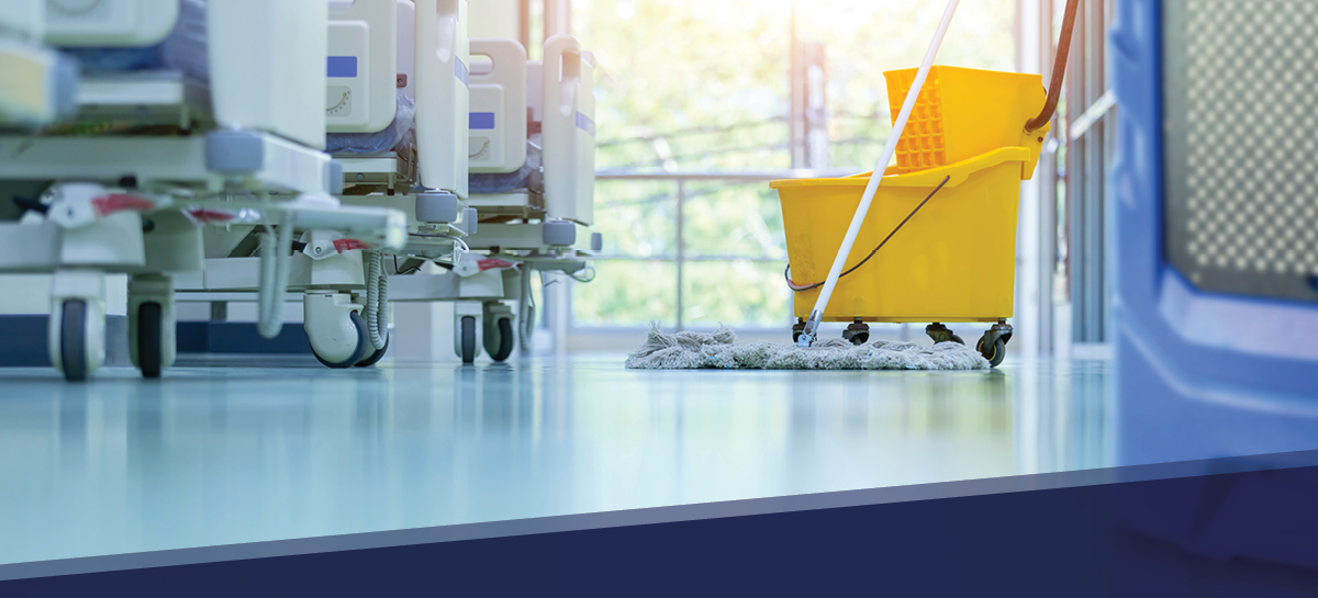 Hospital hallway with cleaning equipment and mop bucket positioned between hospital beds, representing flood cleanup and restoration efforts