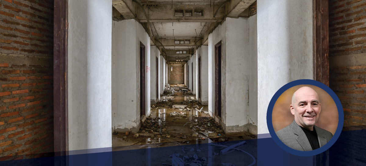 Flood-damaged building hallway filled with debris and standing water, overlaid with a professional headshot of a smiling man in a grey blazer, indicating expert insight or commentary on disaster restoration.