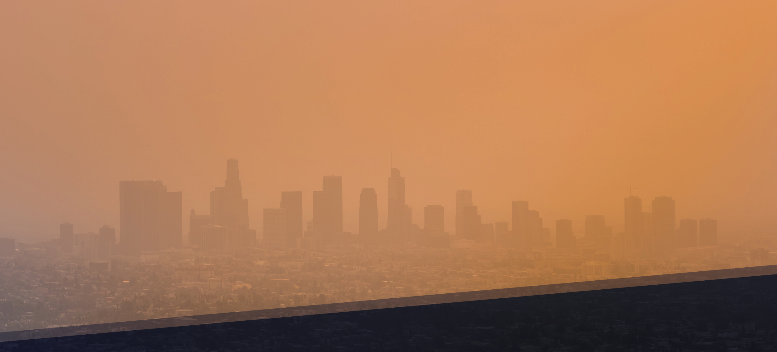 City skyline obscured by thick orange haze from wildfire smoke, illustrating poor air quality and elevated pollution levels. Highlights environmental impact of wildfires on urban air and the need for effective indoor air filtration solutions.